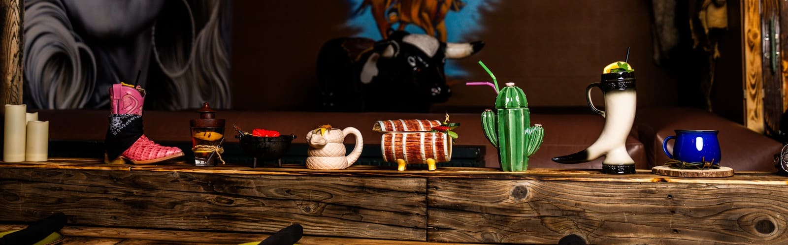 Western-themed bar display featuring novelty cocktail glasses including cactus, boot, and horn-shaped drinkware